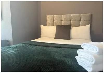 a bedroom with a bed with a green comforter at Hotel Anfield in Liverpool