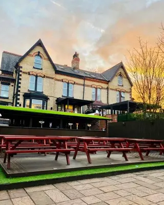a group of red picnic tables in front of a building at Hotel Anfield in Liverpool