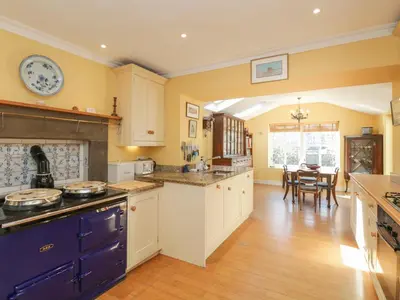 a large kitchen with yellow walls and wooden floors at The White House in Grange Over Sands