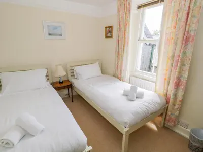 two beds in a room with a window at The White House in Grange Over Sands