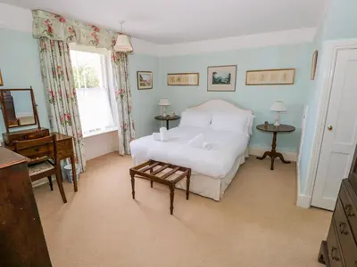a bedroom with a white bed and a piano at The White House in Grange Over Sands