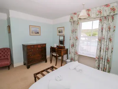 a bedroom with a bed and a dresser and a window at The White House in Grange Over Sands