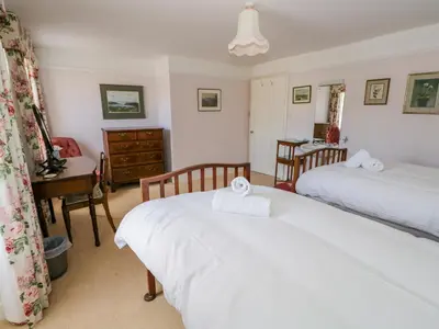 a bedroom with two beds and a desk and a table at The White House in Grange Over Sands