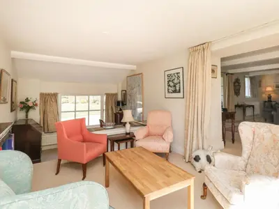 a living room with pink chairs and a table at The White House in Grange Over Sands