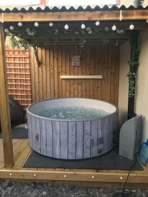 a jacuzzi tub in a wooden enclosure with a television at My Perfect Place Rooms & Apartments -Some rooms with Hot Tub- Free Parking in Blackpool