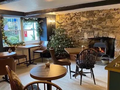 a restaurant with tables and chairs and a fireplace at Coffee & Stays at Cartmel Square in Cartmel