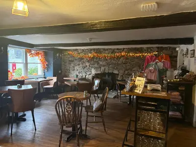 a restaurant with tables and chairs and a stone wall at Coffee & Stays at Cartmel Square in Cartmel