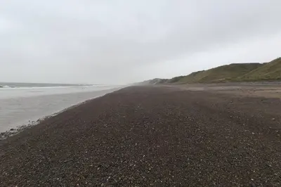 an empty beach with the ocean in the background at Unique, cosy, Lake District artist hideaway - 5 bd in Millom