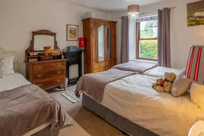 a bedroom with two beds with a teddy bear on it at The Old Post Office in Grange Over Sands