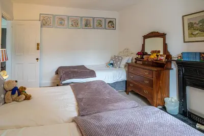 a bedroom with two beds and a dresser and a mirror at The Old Post Office in Grange Over Sands