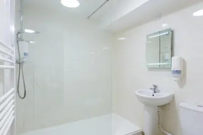 a white bathroom with a shower and a sink at Hotel Santa Maria - formerly Daishs Blackpool in Blackpool