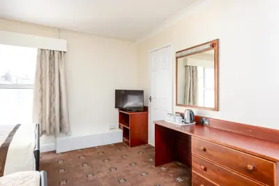 a hotel room with a bed and a mirror and a dresser at Hotel Santa Maria - formerly Daishs Blackpool in Blackpool