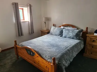 a bedroom with a wooden bed with blue pillows at Brown Cow Apartment in Dalton in Furness