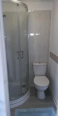 a bathroom with a toilet and a glass shower at Northdene Theatre Hotel in Blackpool
