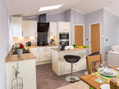 a kitchen with white cabinets and a table and chairs at Waternook Lodge in Carnforth