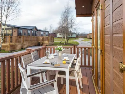 a white table and chairs on a wooden deck at Waternook Lodge in Carnforth