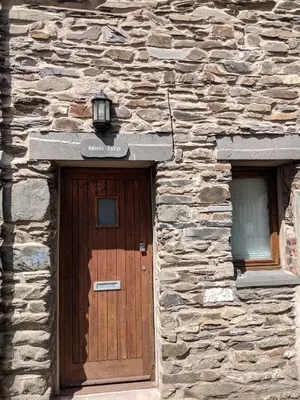 a stone building with a wooden door and two windows at Moss Tarn in Ulverston