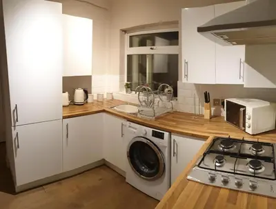 a kitchen with white cabinets and a washer and a stove at 4 Bedrooms, Sleeps 10, Near LFC & EFC in Liverpool