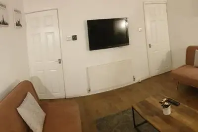a living room with a couch and a tv on a wall at 4 Bedrooms, Sleeps 10, Near LFC & EFC in Liverpool
