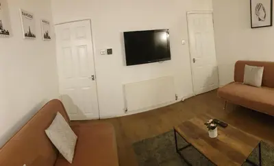 a living room with a couch and a tv on a wall at 4 Bedrooms, Sleeps 10, Near LFC & EFC in Liverpool
