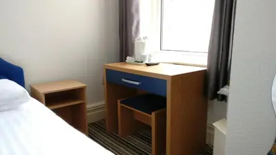 a bedroom with a desk with a window and a bed at OYO Wave Crest Hotel in Blackpool