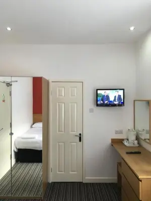 a room with a bed and a television on a wall at OYO Wave Crest Hotel in Blackpool