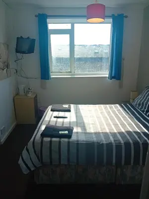 a small bedroom with a bed with a window at MyRoomz New Discovery Hotel in Blackpool