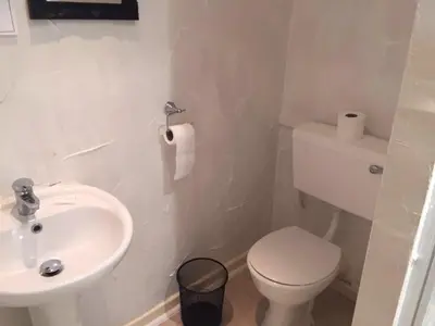 a white bathroom with a toilet and a sink at MyRoomz New Discovery Hotel in Blackpool