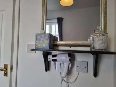 a shelf with a hair dryer and a mirror at The Cameo in Blackpool