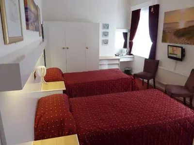 a hotel room with two beds and two chairs at The Regal Hotel in Blackpool