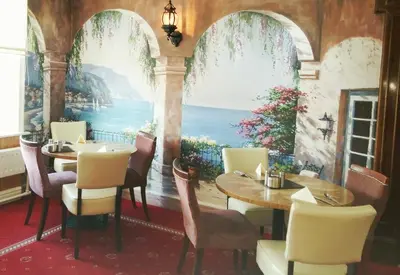 a dining room with a table and chairs and a painting at The Regal Hotel in Blackpool