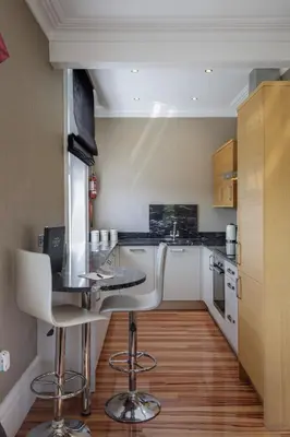 a kitchen with a counter and two bar stools at Breck Apartments by Central Beach Leisure Ltd in Poulton le Fylde