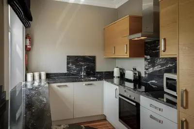 a kitchen with white cabinets and black counter tops at Breck Apartments by Central Beach Leisure Ltd in Poulton le Fylde