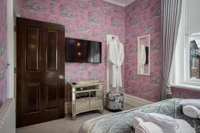 a bedroom with pink wallpaper and a bed and a tv at Breck Apartments by Central Beach Leisure Ltd in Poulton le Fylde