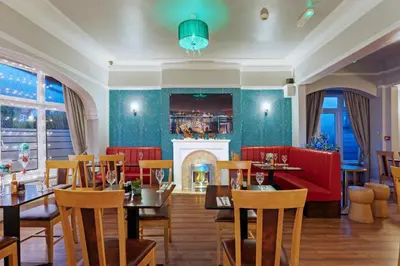 a restaurant with tables and chairs and a fireplace at Orrell Park Hotel in Liverpool
