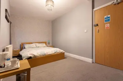a bedroom with a bed and a desk and a door at Orrell Park Hotel in Liverpool