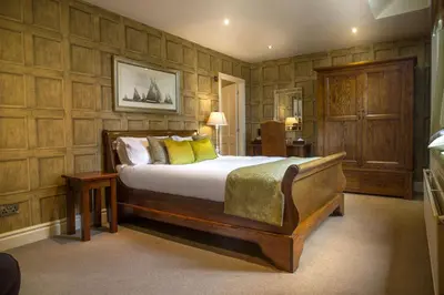 a bedroom with a large bed and wooden walls at Mitton Hall Hotel in Clitheroe