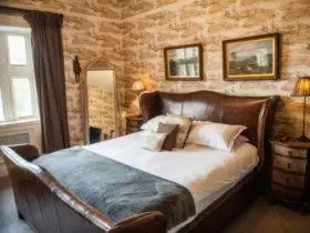 a bedroom with a large bed in a stone wall at Mitton Hall Hotel in Clitheroe