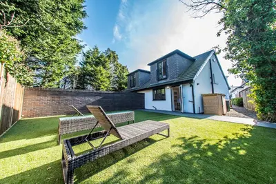 a yard with two benches in front of a house at Courtyard Holiday Homes in Southport