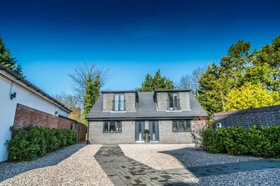 a large brick house with a driveway at Courtyard Holiday Homes in Southport