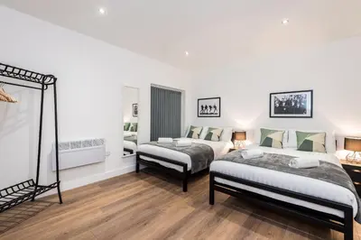 a bedroom with two beds and a mirror at SGT Peppers Mathew Street Apartments By Happy Days in Liverpool