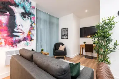 a living room with a couch and a painting on the wall at SGT Peppers Mathew Street Apartments By Happy Days in Liverpool