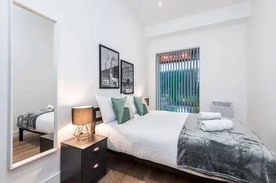 a bedroom with a large bed and a mirror at SGT Peppers Mathew Street Apartments By Happy Days in Liverpool