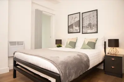 a bedroom with a large bed with two pictures on the wall at SGT Peppers Mathew Street Apartments By Happy Days in Liverpool