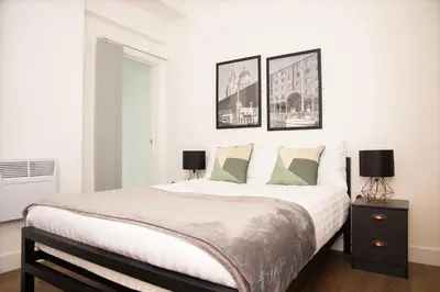 a white bedroom with a large bed with two lamps at SGT Peppers Mathew Street Apartments By Happy Days in Liverpool