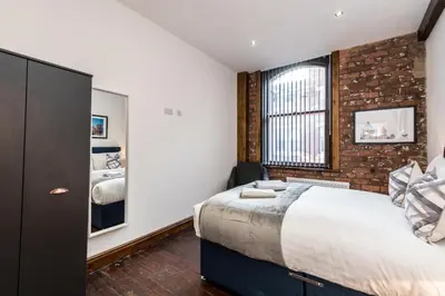 a bedroom with a large bed and a brick wall at 27 Stanley Street Aparthotel by UStay in Liverpool