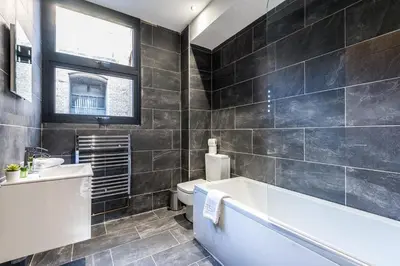 a bathroom with a tub and a toilet and a sink at 27 Stanley Street Aparthotel by UStay in Liverpool