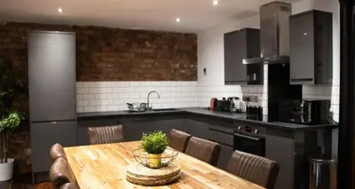 a kitchen with a wooden table with chairs and a table sidx sidx sidx at 27 Stanley Street Aparthotel by UStay in Liverpool
