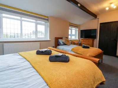 a bedroom with two beds and a flat screen tv at Mayfield Cottage in Blackpool