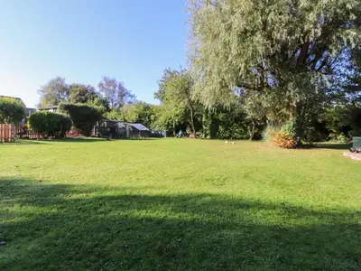 a large grass field with a tree in the background at Mayfield Cottage in Blackpool